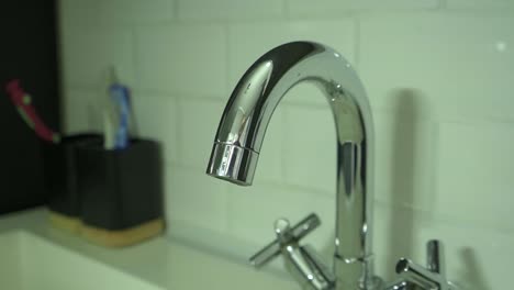 modern aluminium bathroom sink with toothbrushes and tooth paste in the background cup