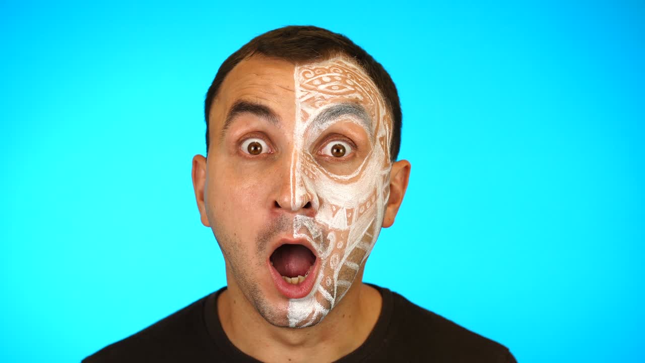 Man with painted face is screaming scared then screaming in anger against blue background