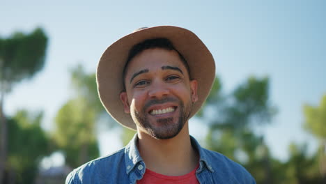 close-up portrait of a smiling man in a hat outdoors