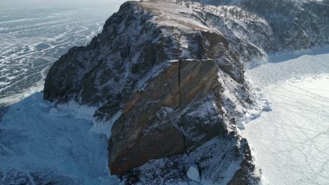 aerial orbital shot of cape khoboy, olkhon island. tall rocks in frozen lake baikal. popular touristic destination. winter landscape. panoramic view