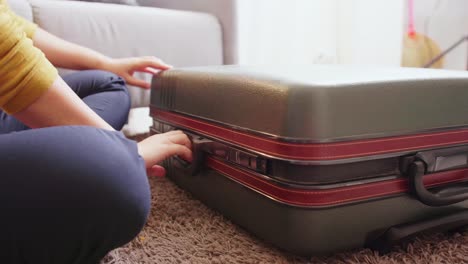 detail of female hands closing suitcase with clothes