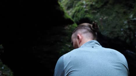 back view of young man slowly walking further into a shadowy ravine