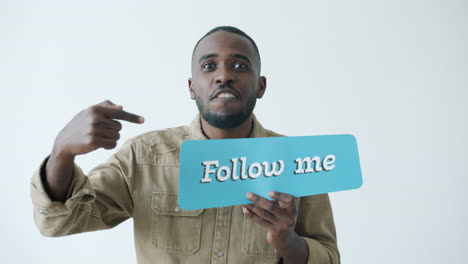 man holding a sign that says "follow me" with a happy expression