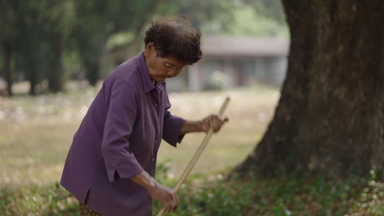Mujer mayor barriendo al aire libre