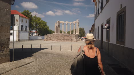 woman walks toward roman ruin