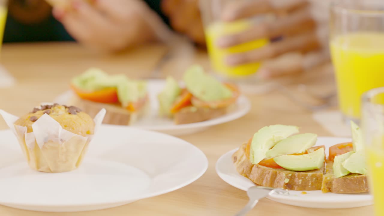 A breakfast or brunch spread featuring avocado toast, muffins, and orange juice