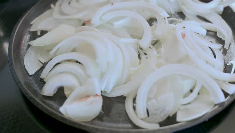 salsa de cebollas blancas en rodajas en aceite en una sartén de hierro fundido en la estufa, casera