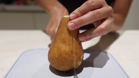 person slicing a pear on a cutting board