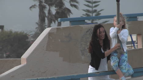 A-mother-helps-her-daughter-hang-on-to-a-zipline-then-watches-her-as-she-rides-away-laughing