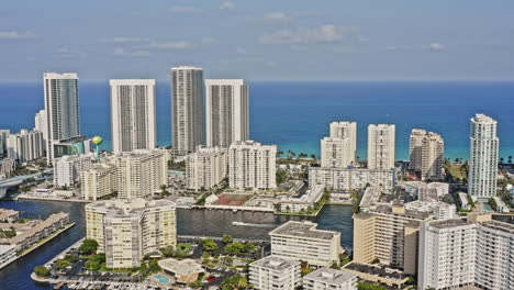 Hallandale-Beach-Florida-Aerial-v4-establishing-pull-out-shot-capturing-beachfront-residential-towers,-urban-cityscape-and-atlantic-ocean,-reveals-a-boat-cruising-on-intracoastal-waterway---March-2021