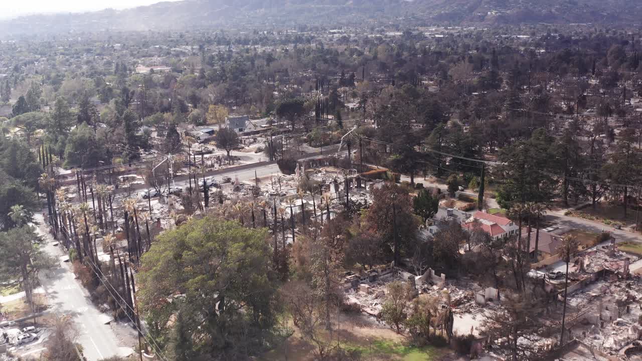 Low aerial shot flying over burned homes and businesses in the Altadena wildfire burn zone in Southern California. 4K