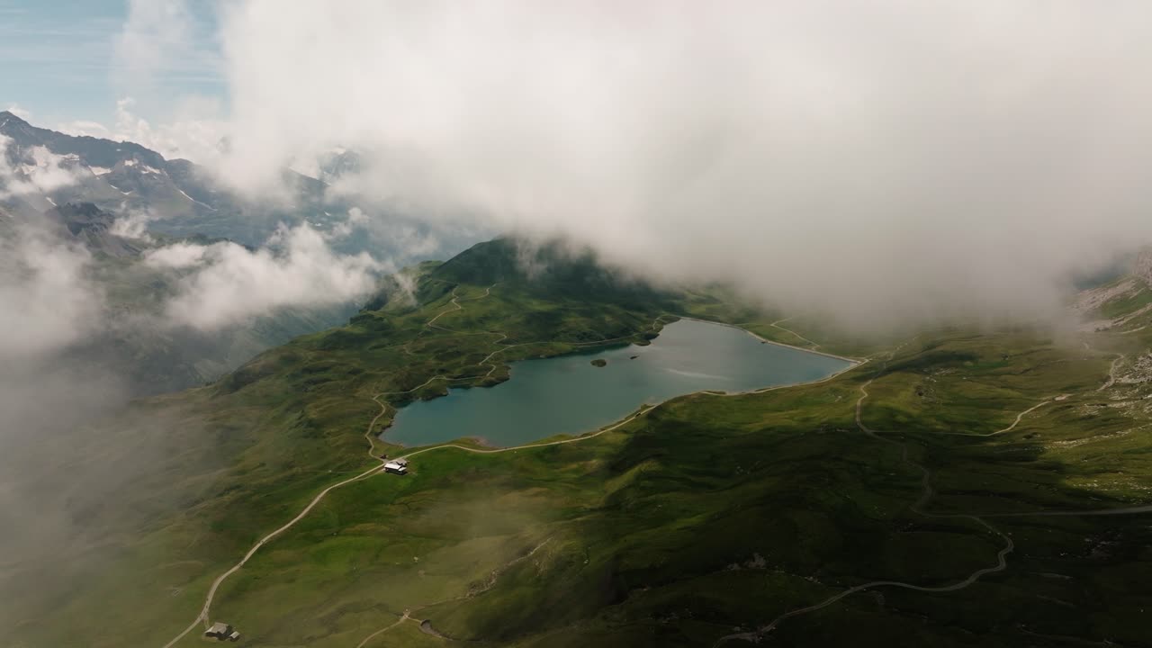 Aerial drone shot through drifting clouds revealing Melchsee-Frutt alpine lake and valley in Switzerland
