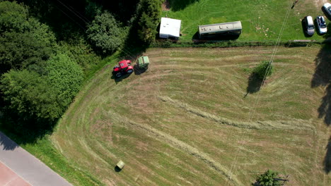 a tractor with baler at work on a freshly mown meadow - aerial top down