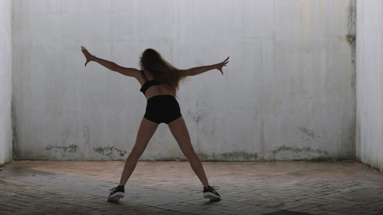 mujer bailarina hermosa joven bailarina de calle caucásica realizando movimientos contemporáneos disfrutando de la expresión de la danza moderna practicando en un almacén grungy