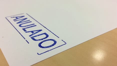 a hand stamping a paper with the message of canceled in spanish anulado