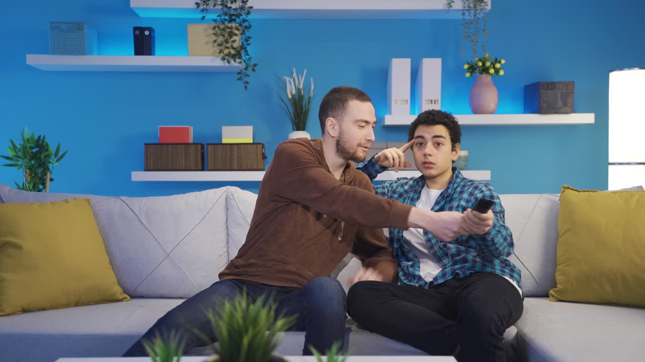 hermanos jóvenes divertidos peleando por ver televisión en casa. conflicto entre hermanos.