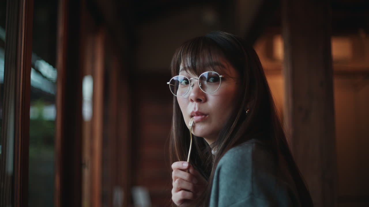 Portrait of an Asian woman with glasses holding a fork