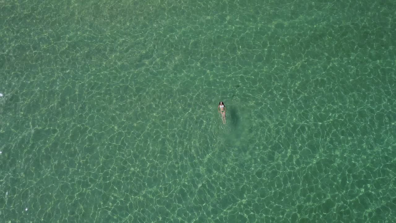 tiro de dron giratorio de una hermosa mujer nadando de espaldas en el mar egeo