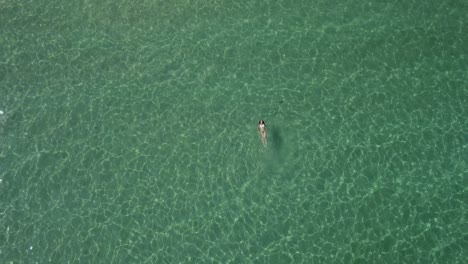 tiro de dron giratorio de una hermosa mujer nadando de espaldas en el mar egeo