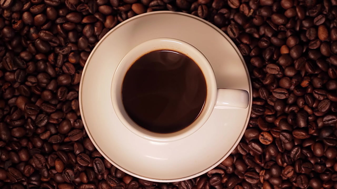 Varm dampende kaffe i en kopp og et landskap av kaffebønner