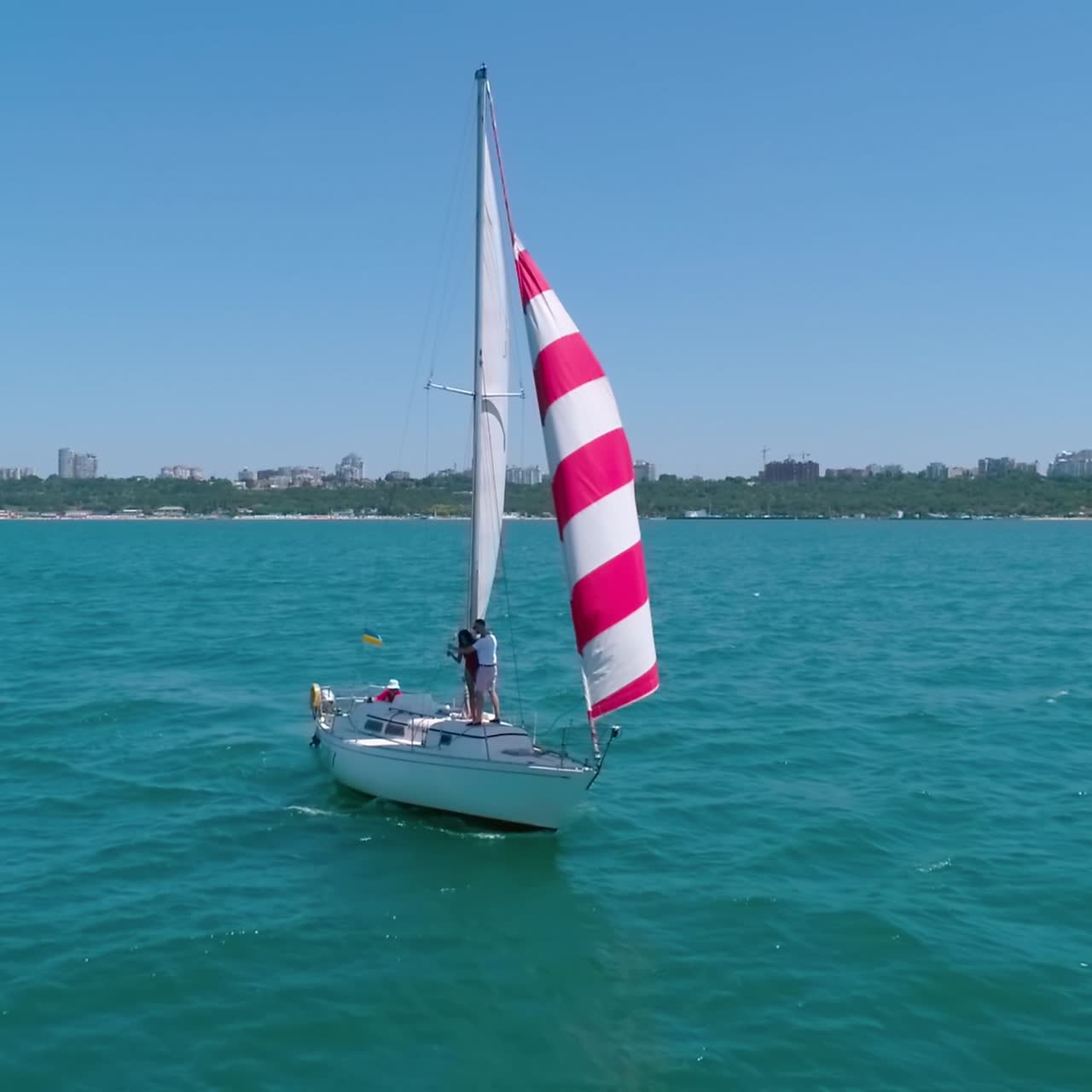 Yacht sailing on sea. Red and white sails on a boat at windy day. Sun shine over sail boat at ocean bay. Sailboat cruise on a beautiful seascape. Ship in summer sunny day