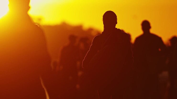 Silhouetted crowd of people walking at sunset