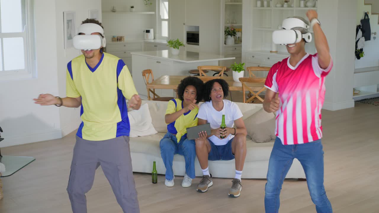 Amici a casa che giocano a un gioco VR, reagendo ai comandi VR mentre altri guardano un tablet e tengono in mano una birra
