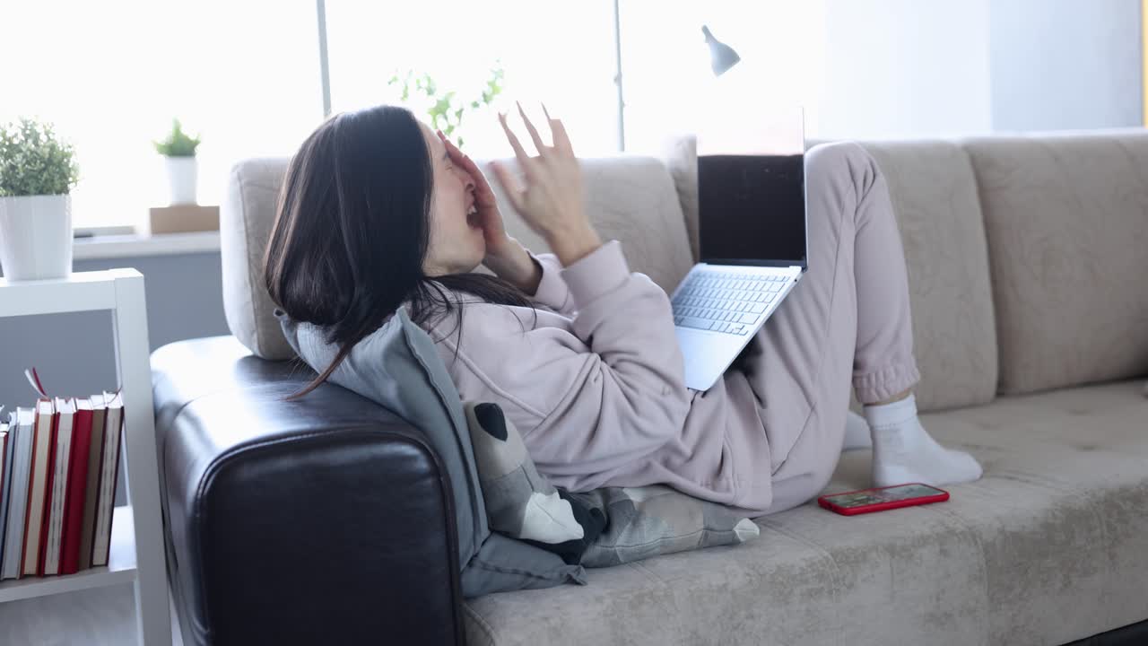 여성이 노트북으로 소파에서 휴식을 취하고 있습니다.