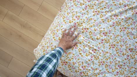 person making a bed with floral bed sheet