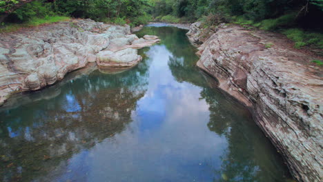 Tranquil-river-flowing-through-Cajones-de-Chame,-Panama,-with-rocky-banks-and-lush-trees