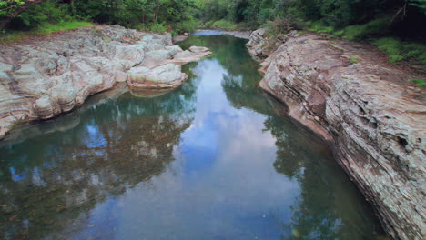 tranquil river flowing through cajones de chame, panama, with rocky banks and lush trees