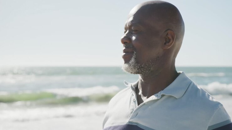 Happy senior african american man smiling at beach, in slow motion