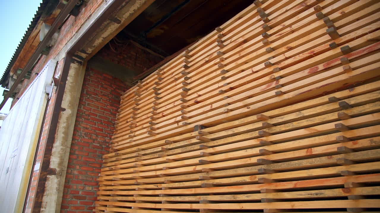 Wooden planks piled in the warehouse. Sight of an open barn filled with wood for manufacturing doors.
