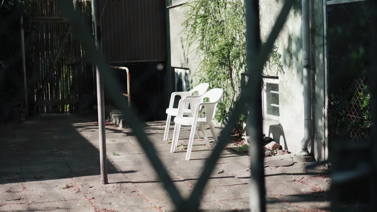White garden chairs in the sun with the trees shadows dancing