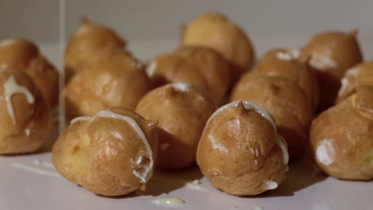 Profiteroles with glaze. Profiterole cakes with custard are sprinkled with sugar creme. Sweet dessert with moist filling whipped cream