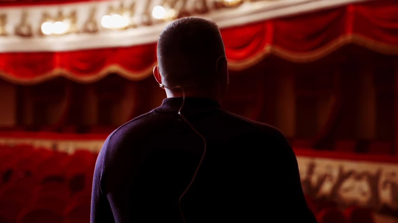 Man entertainer, presenter or actor on stage. Active gestures of clapping to the auditorium. View of a male public speaker speaking at the microphone.