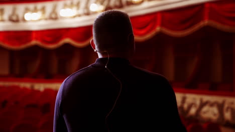 man entertainer, presenter or actor on stage. active gestures of clapping to the auditorium. view of a male public speaker speaking at the microphone.