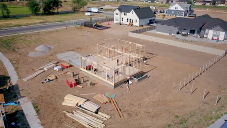 a drone shot backing away from framers putting up walls on a new home in the process of being built