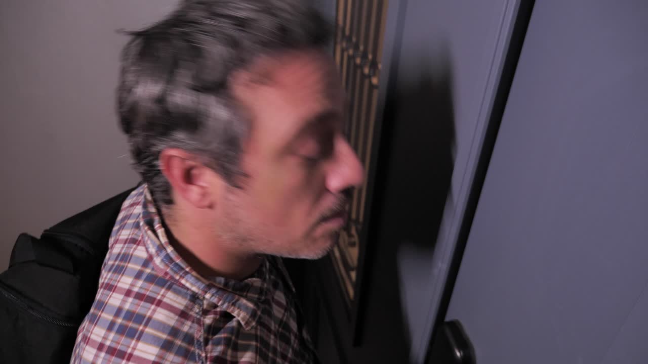 vuelve a casa, el hombre hace una expresión de sorpresa, abre la puerta y entra en el apartamento