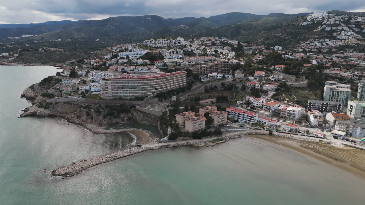 Sweeping aerial over Playa Sur homes and coastline with beach curve and palm trees