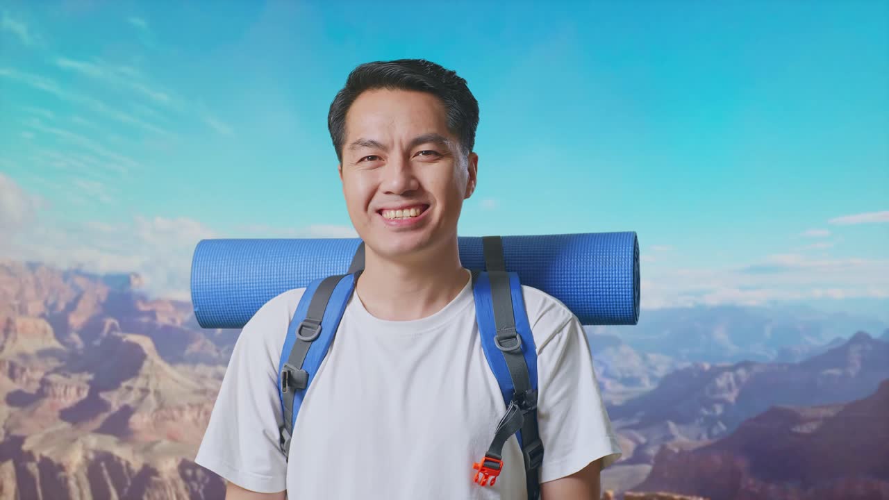 Close Up Of Asian Male Hiker With Mountaineering Backpack Smiling To Camera While Traveling At The Top Of Mountain
