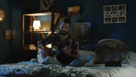 couple singing and playing guitar in bedroom at night