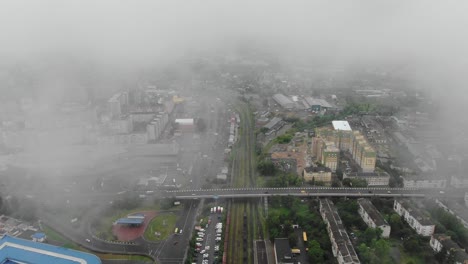 aerial view of city infrastructure with roads, railroad tracks, and buildings on a foggy day