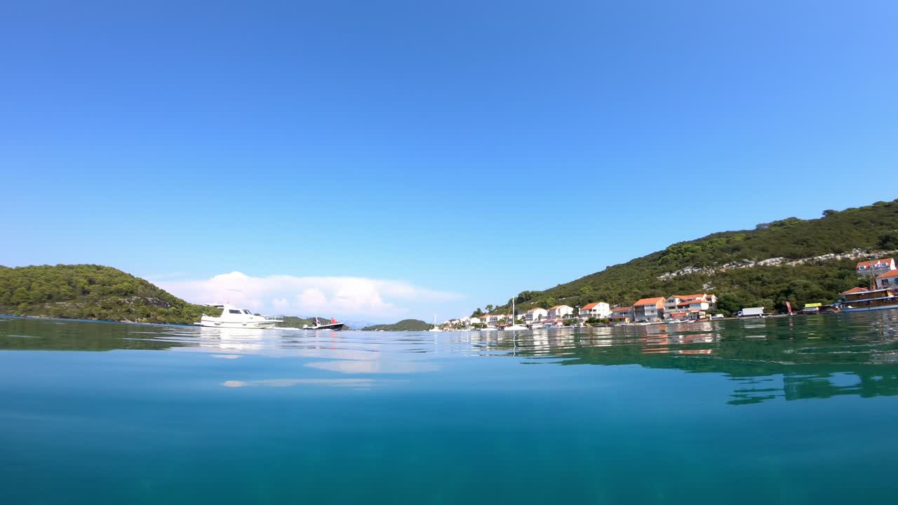 A small boat approaches village Polace, island Mljet in Croatia. It is a beautiful sunny day and the view is from sea level.
