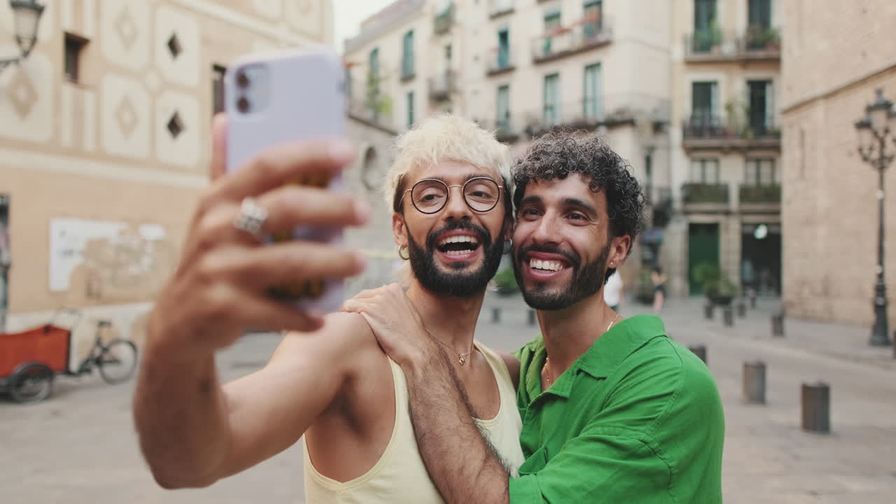 Coppia gay felice che si scatta un selfie in una strada di città europea