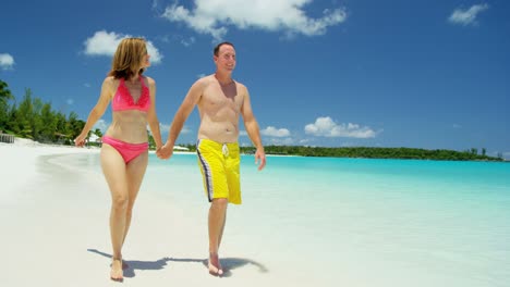 caucasian couple in swimwear holding hands on beach