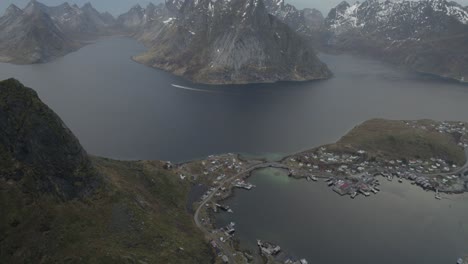 Luftaufnahme-Mit-Blick-Auf-Das-Dorf-Reine-Und-Die-Berge,-Die-Es-Umgeben,-Auf-Den-Bewölkten-Lofoten,-Norwegen---Neigung,-Drohnenaufnahme