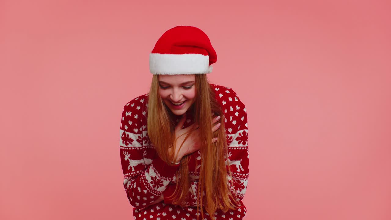 크리스마스 스웨터를 입은 사랑스러운 긍정적인 성인 소녀가 우스 ⁇ 스러운 농담을 듣고 크게 웃고 있습니다.
