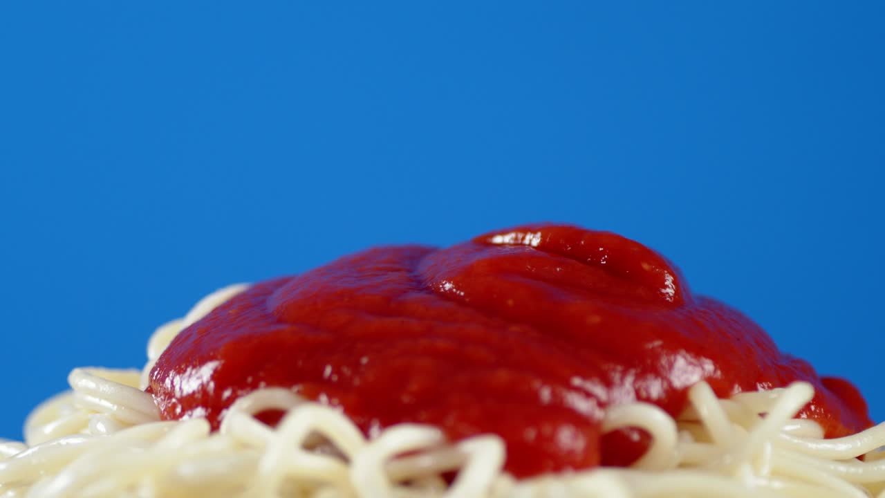 La salsa di pomodoro viene versata sugli spaghetti bolliti.