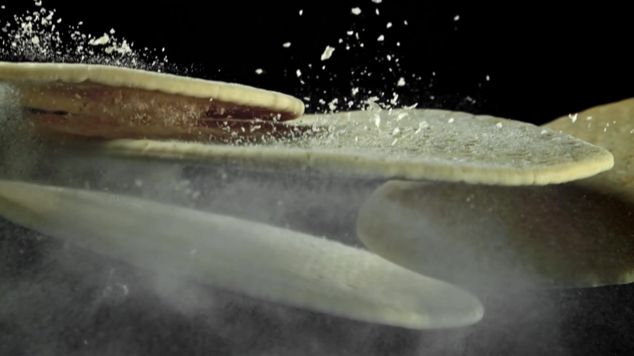 Rå tortillas falder med melstøv på sort baggrund